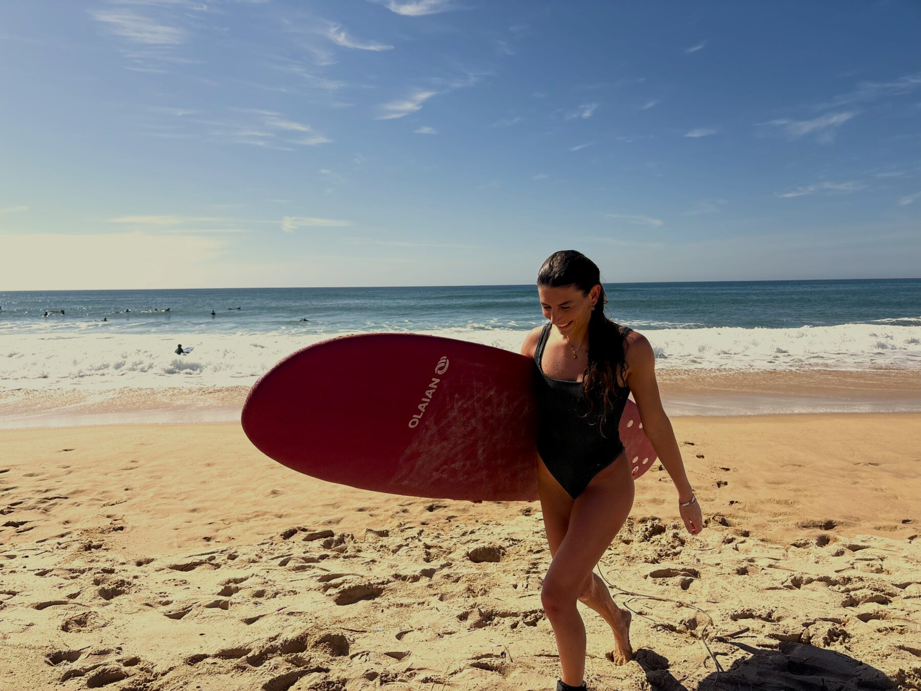 Francesca returning from the sea with a surfboard